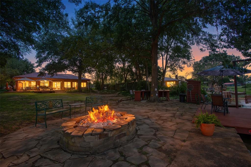 The property features a stone patio with a built-in fire pit, a spacious lawn area, and mature trees