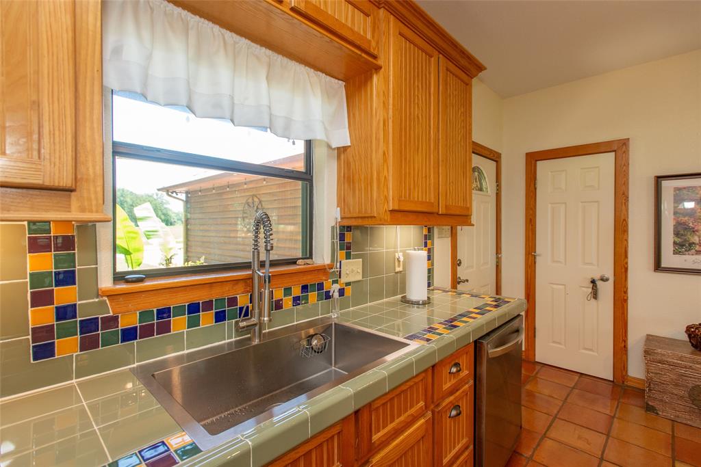 121 Xit Ranch Road Trinidad, TX 75163 - Photo 11 of 40 The kitchen features warm wood cabinetry, a stainless steel sink with a gooseneck faucet, and tiled countertops