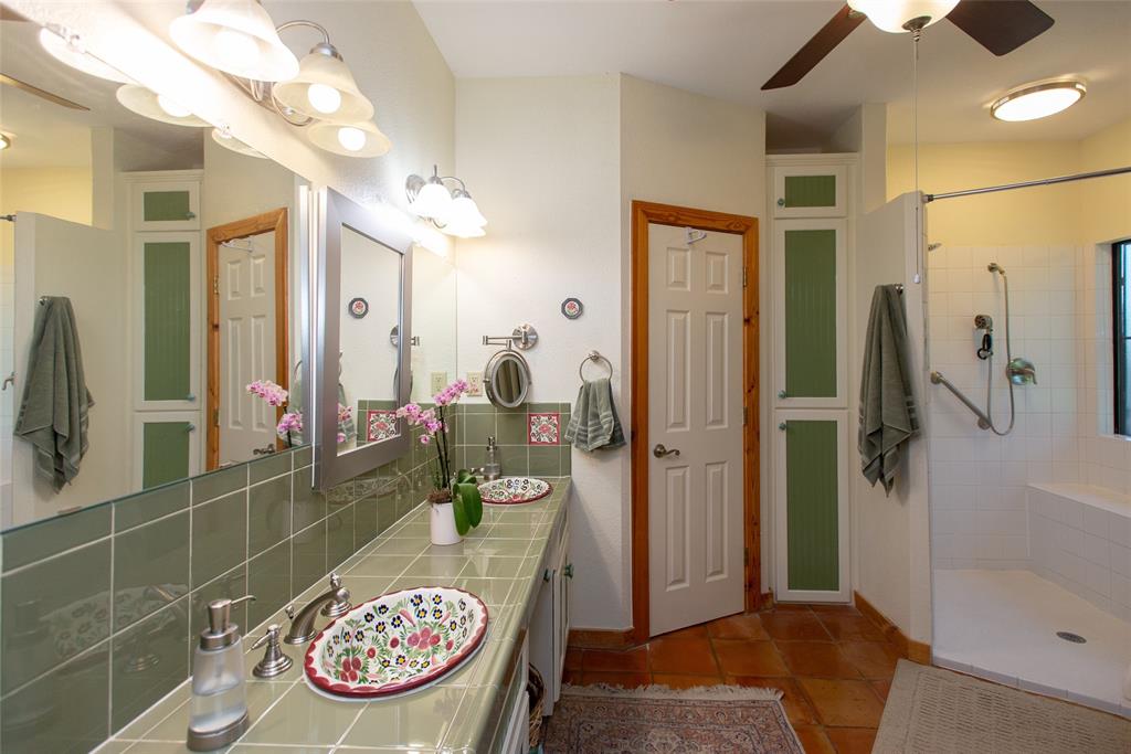 121 Xit Ranch Road Trinidad, TX 75163 - Photo 15 of 40 Bathroom featuring a dual vanity with decorative sinks, green tiled countertops and backsplash, and an enclosed shower with a built-in bench