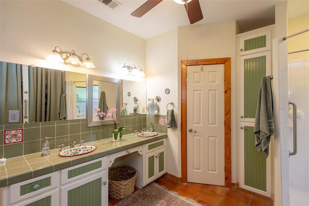 121 Xit Ranch Road Trinidad, TX 75163 - Photo 16 of 40 The bathroom features a double vanity with tile countertops and sinks, a full-width mirror, and a ceiling fan