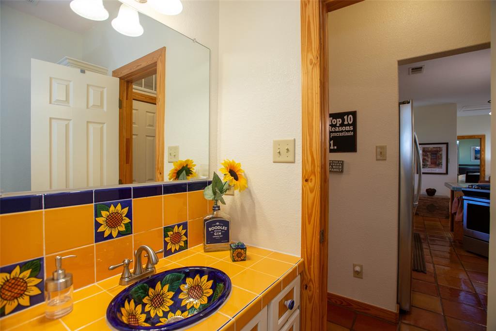 121 Xit Ranch Road Trinidad, TX 75163 - Photo 19 of 40 Bathroom vanity featuring a decorative sunflower-patterned sink and matching countertop tiles, complemented by a large wall mirror and overhead lighting