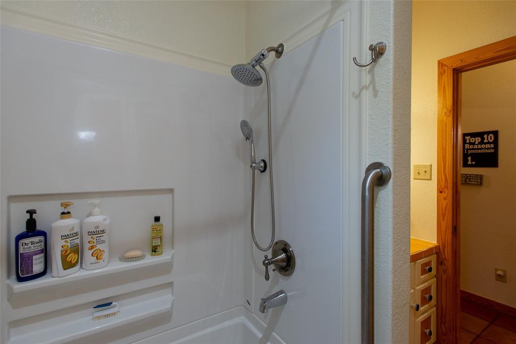 121 Xit Ranch Road Trinidad, TX 75163 - Photo 20 of 40 Bathroom featuring a shower and bathtub combination with a built-in shelf and grab bar