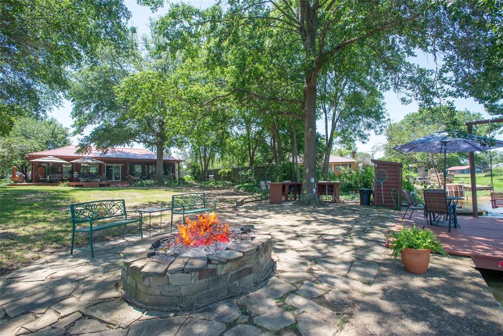 121 Xit Ranch Road Trinidad, TX 75163 - Photo 32 of 40 The property features a stone fire pit, a stone patio, and a wooden deck