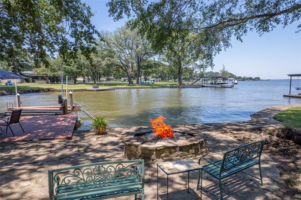 121 Xit Ranch Road Trinidad, TX 75163 - Photo 34 of 40 The property features a stone patio area with a fire pit overlooking the water