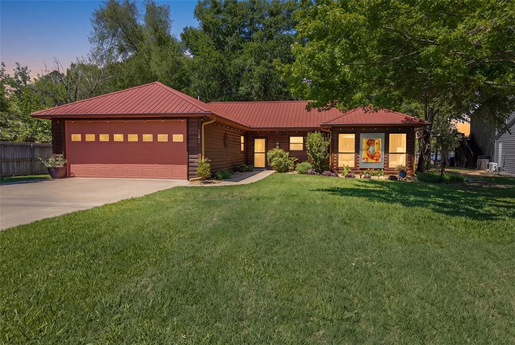 121 Xit Ranch Road Trinidad, TX 75163 - Photo 37 of 40 The property features a red metal roof, a wooden exterior, and a well-maintained lawn