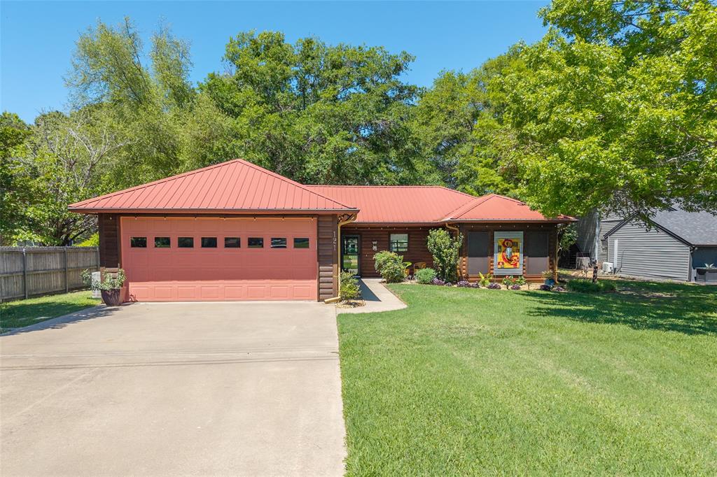 121 Xit Ranch Road Trinidad, TX 75163 - Photo 38 of 40 This property features a red metal roof, a two-car garage with a drive, and a well-maintained lawn