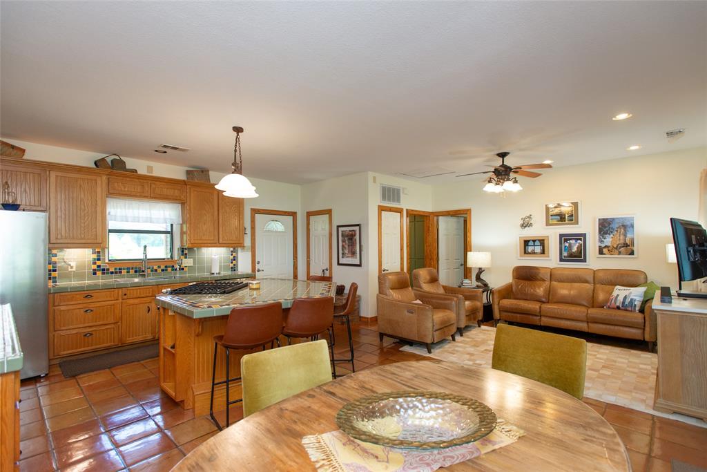 121 Xit Ranch Road Trinidad, TX 75163 - Photo 4 of 40 Open concept living area featuring a kitchen with wooden cabinetry, an island with a tiled countertop, and terracotta tile flooring