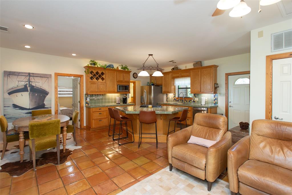 121 Xit Ranch Road Trinidad, TX 75163 - Photo 6 of 40 The open concept interior features tile flooring, a kitchen with wooden cabinetry, a central island with bar seating, and recessed lighting