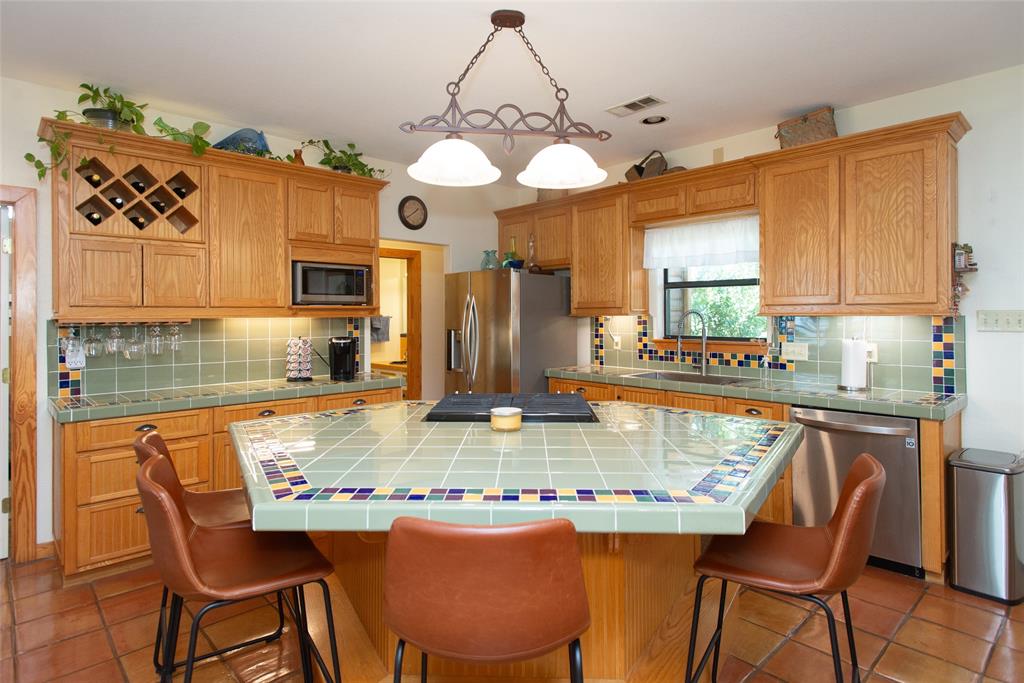 121 Xit Ranch Road Trinidad, TX 75163 - Photo 7 of 40 The kitchen features a tiled island with seating, oak cabinetry, and a tiled backsplash