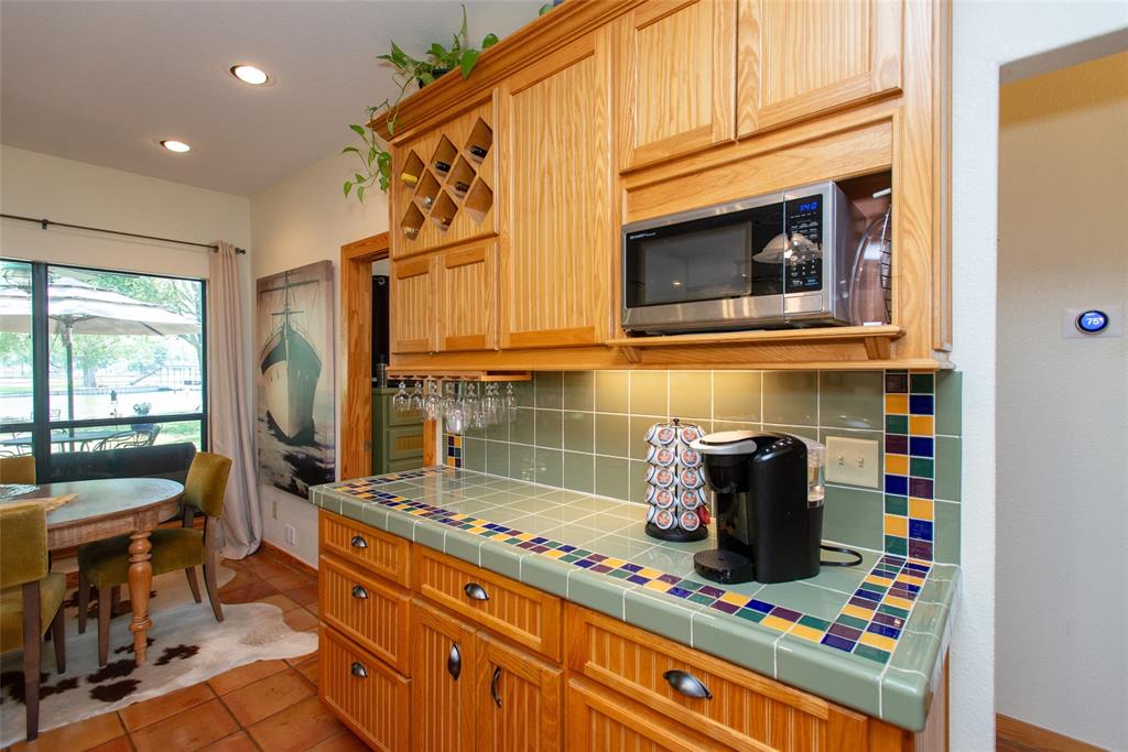 121 Xit Ranch Road Trinidad, TX 75163 - Photo 10 of 40 The property features a kitchen with light wood cabinetry, a built-in microwave, and a tile countertop with decorative accents