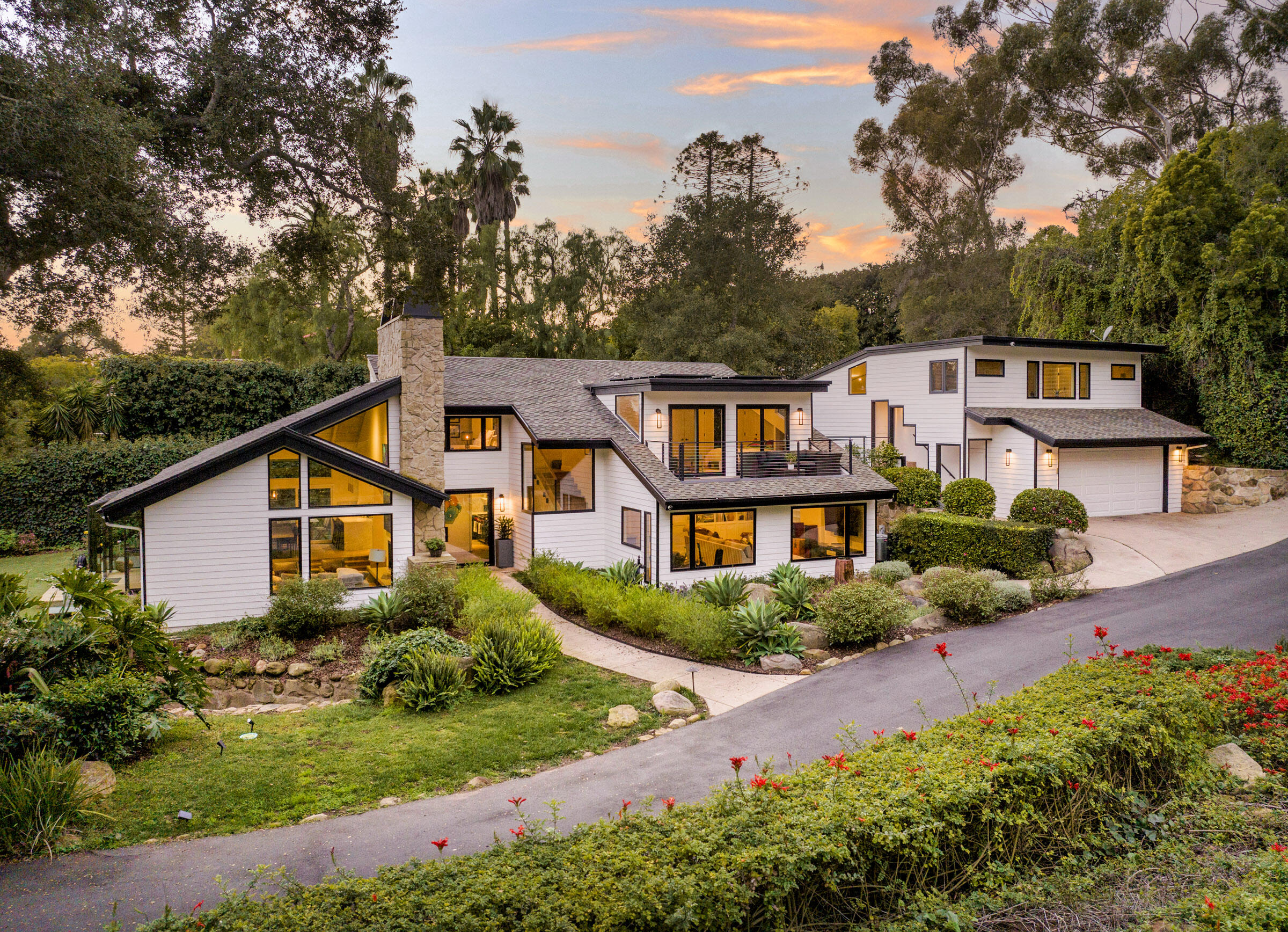 a front view of a house with a yard and mountain view in back