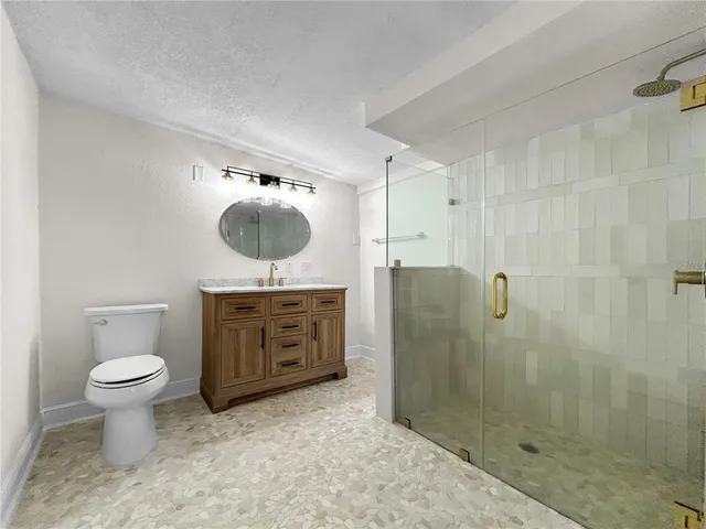 a bathroom with a toilet a sink a mirror and shower