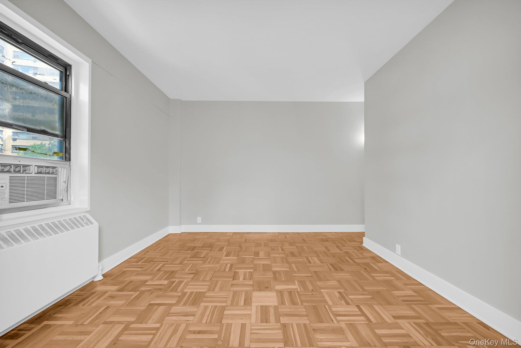 9 Fordham Hill Ovl, Unit 3C Bronx, NY 10468 - Photo 15 of 25 Additional living space with light parquet flooring, radiator heating unit, and cooling unit