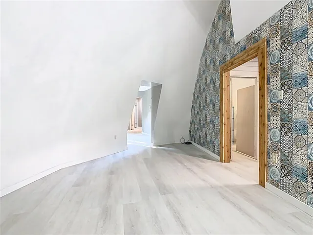 a view of a hallway with wooden floor and a bathroom