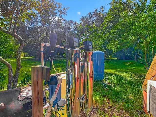 a view of a backyard with table and chairs plants and large tree