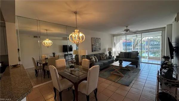 a living room with couches a dining table and a chandelier with kitchen view