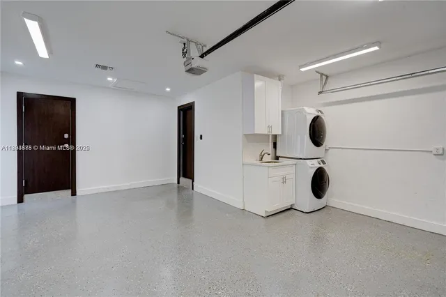 a view of an empty room with kitchen and window