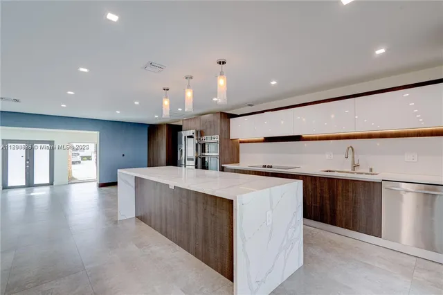 a large kitchen with stainless steel appliances a large counter top a stove a sink and a refrigerator