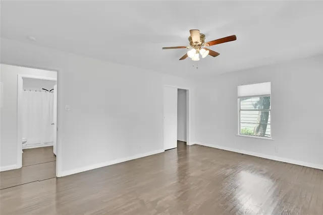 an empty room with wooden floor closet and windows