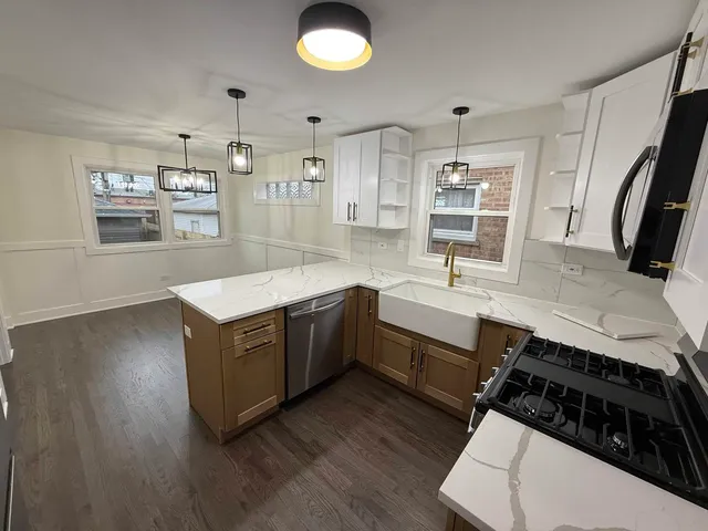 a kitchen with stainless steel appliances granite countertop a sink a stove and a wooden floors