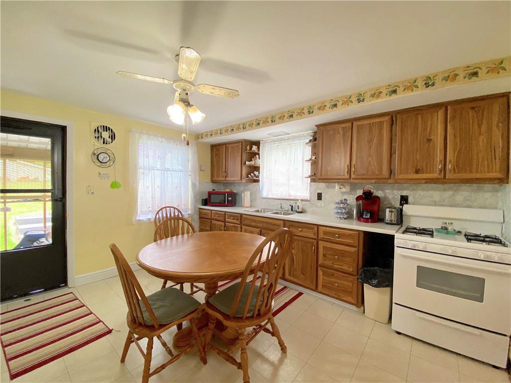 560 Center Hill Road Pittsburgh, PA 15239 - Photo 14 of 25 a kitchen with stainless steel appliances granite countertop a stove top oven a sink a dining table and chairs with wooden floor