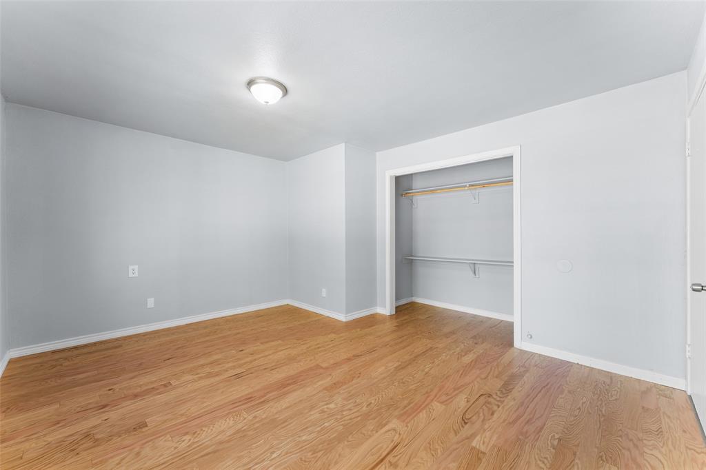 612 East 8th Street Kemp, TX 75143 - Photo 15 of 25 Spacious room featuring wood-finish flooring, light grey wall tones, white trim, and a built-in closet with shelving and hanging rods