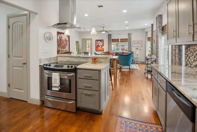 a kitchen with stainless steel appliances granite countertop a stove and a wooden floors