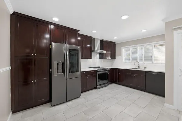 a large kitchen with stainless steel appliances kitchen island granite countertop a refrigerator and a sink