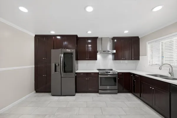 a large kitchen with granite countertop a refrigerator and a sink