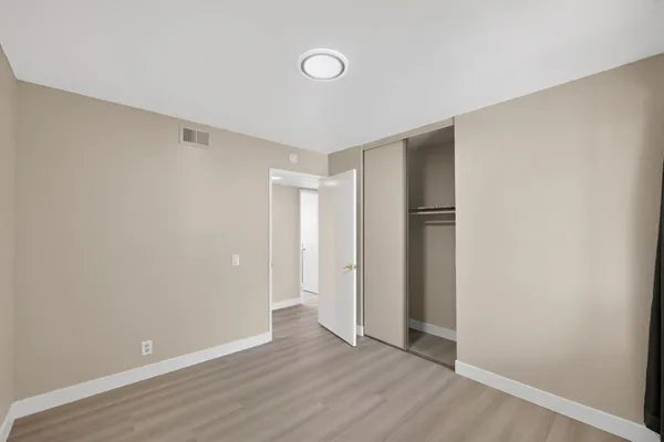 an empty room with wooden floor and mirror
