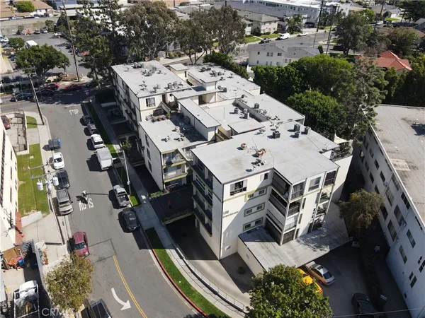 an aerial view of a residential apartment building with a yard and parking spaces