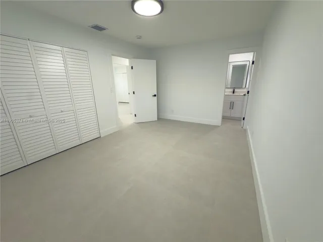 an empty room with a white cabinet and mirrors