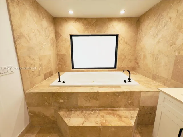 a bathroom with a granite countertop sink and a bathtub