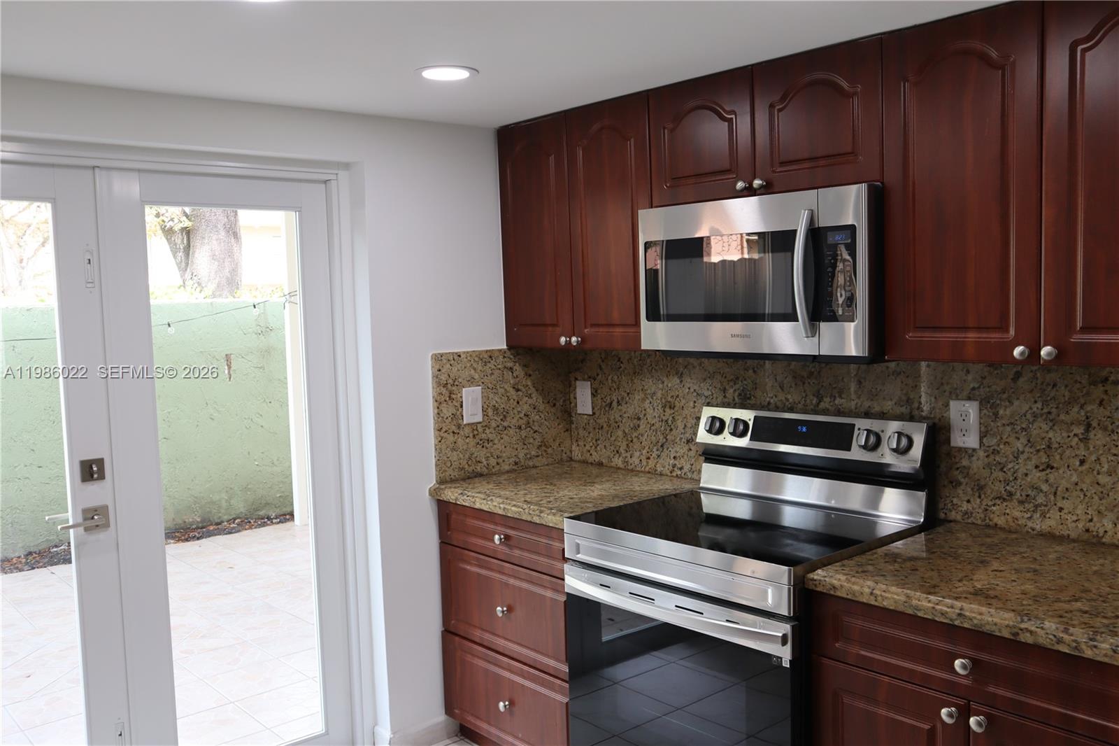 a kitchen with granite countertop wooden cabinets and stainless steel appliances