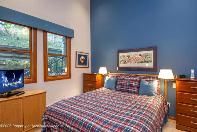 a bedroom with a bed and dresser next to a window