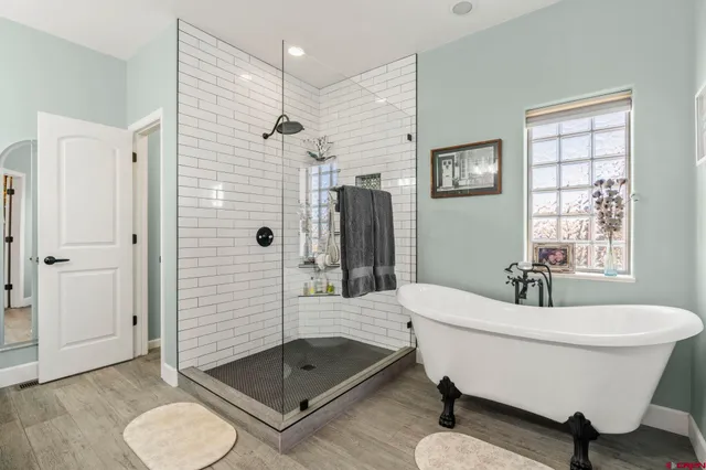 a bathroom with a tub shower sink mirror and toilet