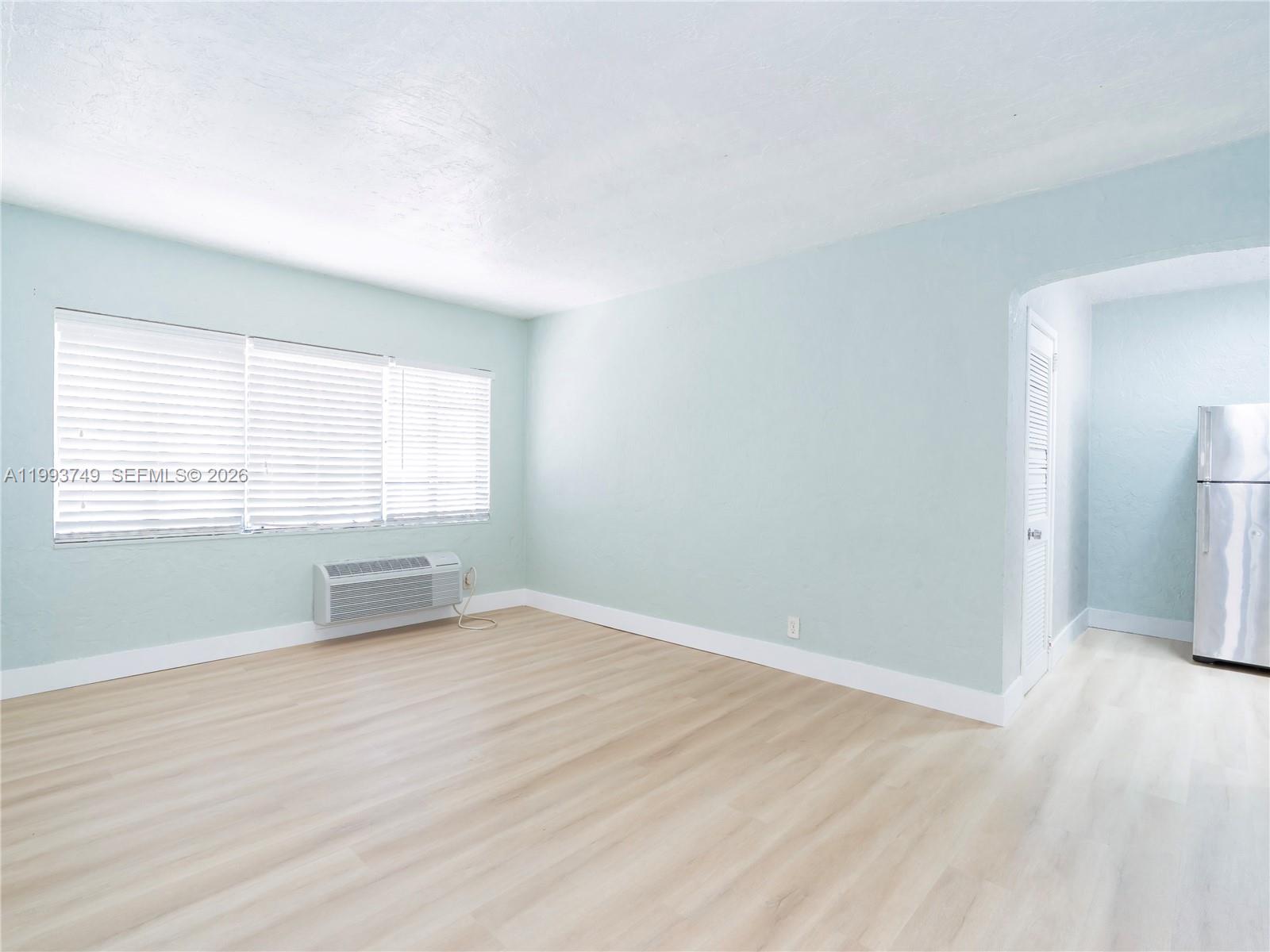 7635 Dickens Avenue, Unit 3 Miami Beach, FL 33141 - Photo 2 of 9 an empty room with wooden floor and windows