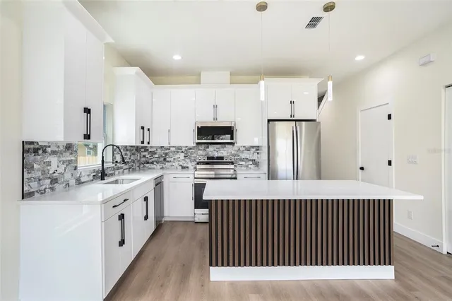 a kitchen with stainless steel appliances granite countertop a sink stove and refrigerator