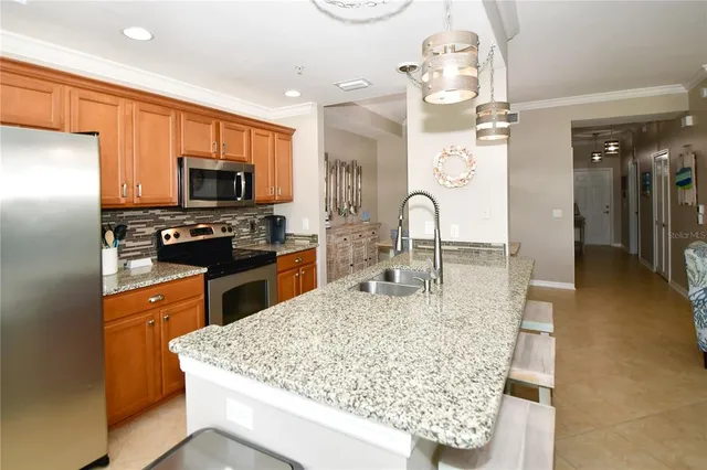 a kitchen with stainless steel appliances kitchen island granite countertop a refrigerator oven a sink dishwasher and white cabinets with wooden floor