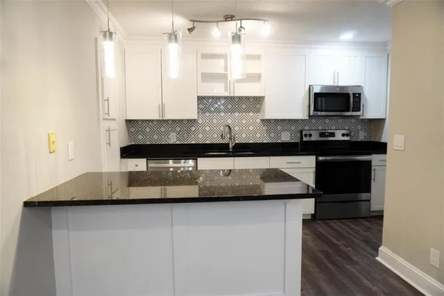a kitchen with kitchen island granite countertop a sink and a stove top oven with wooden floor