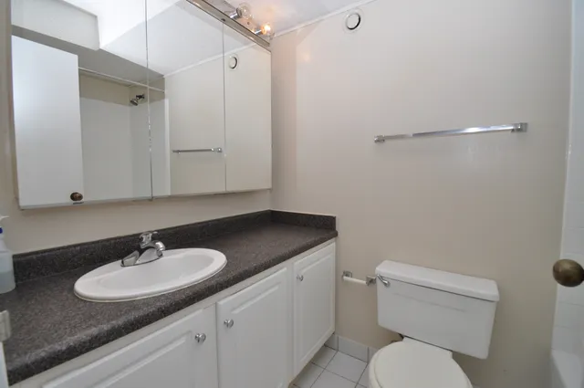 a bathroom with a granite countertop sink a toilet and a mirror
