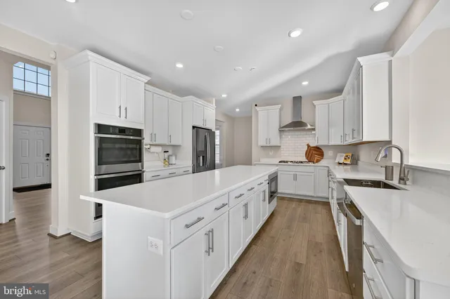 a large kitchen with stainless steel appliances lots of white cabinets and wooden floors