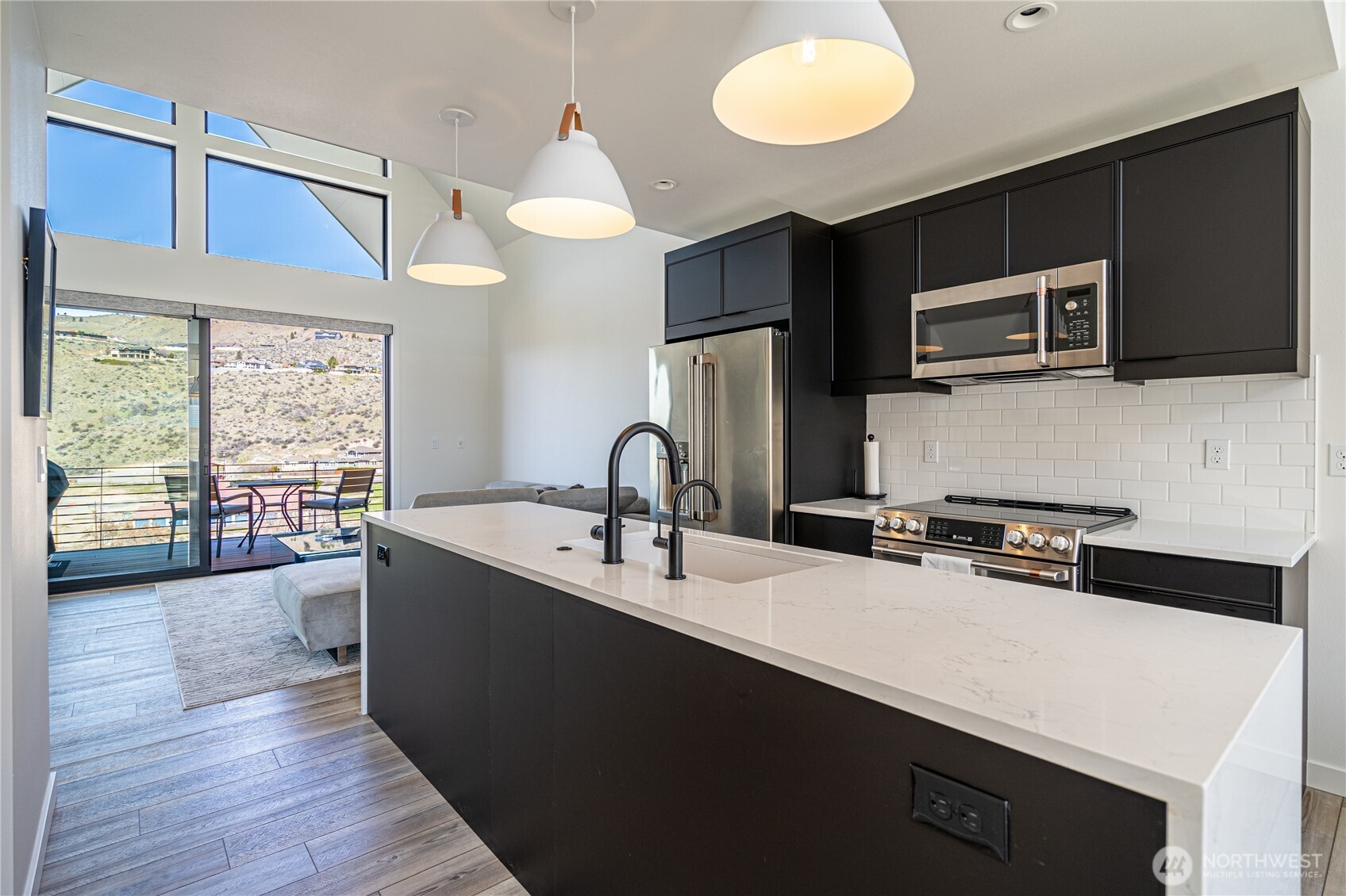1418 Cottage Lane Chelan, WA 98816 - Photo 10 of 40 a kitchen with stainless steel appliances a sink dishwasher a stove a microwave oven and a dining table with wooden floor