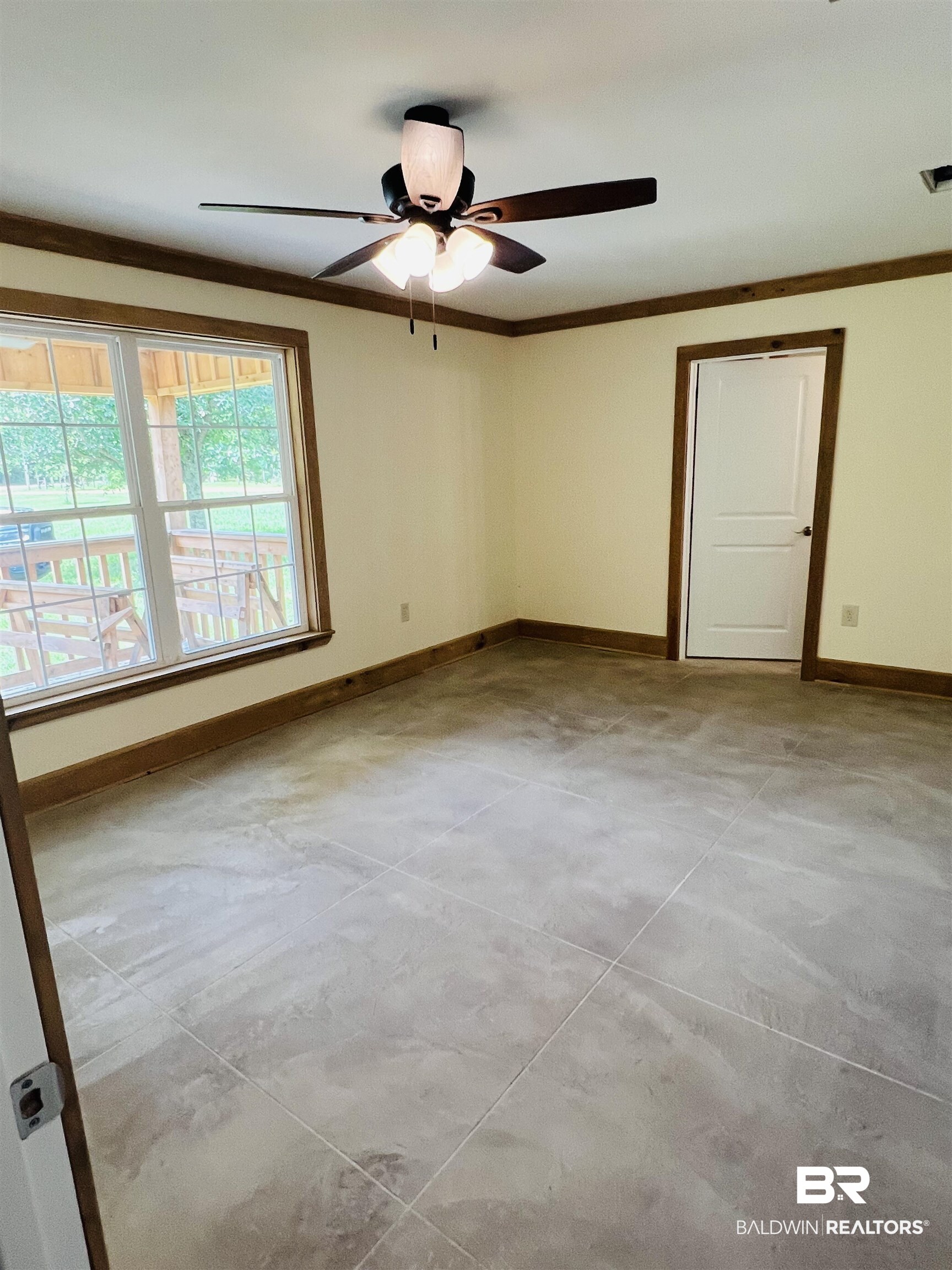 29685 Gardner Road Elberta, AL 36530 - Photo 7 of 16 Spacious room featuring neutral wall paint, wood-finish trim, a ceiling fan with integrated lighting, and large format floor tiles