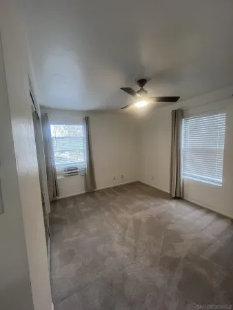 an empty room with windows and refrigerator