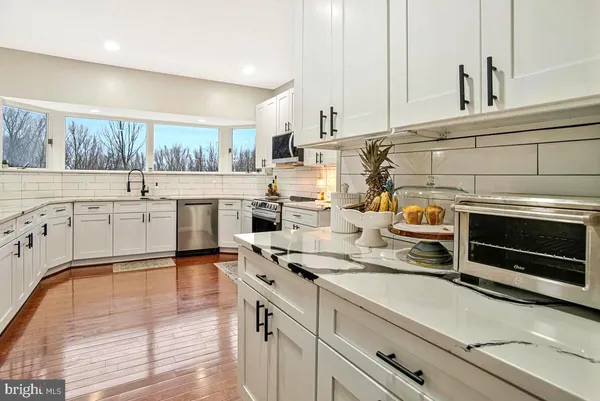 a kitchen with stainless steel appliances granite countertop a refrigerator a sink and white cabinets