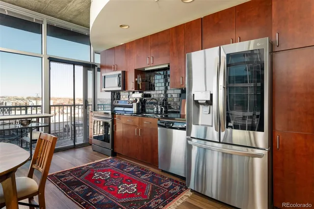 a kitchen with stainless steel appliances granite countertop a refrigerator a stove a sink dishwasher with a dining table and chairs with wooden floor