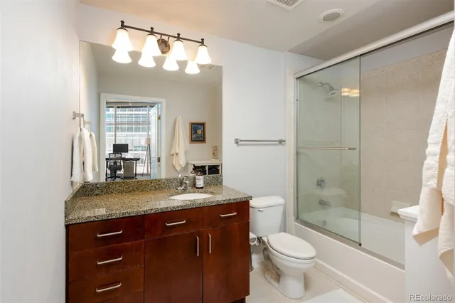 a bathroom with a granite countertop sink toilet mirror and shower