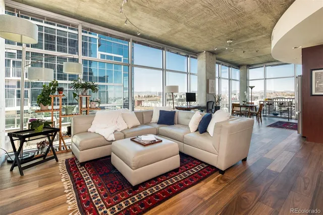 a living room with furniture a large window and wooden floor