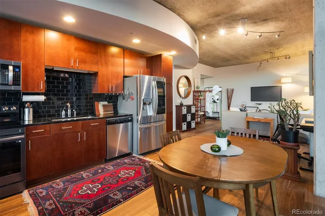 a kitchen with stainless steel appliances wooden floor and a refrigerator